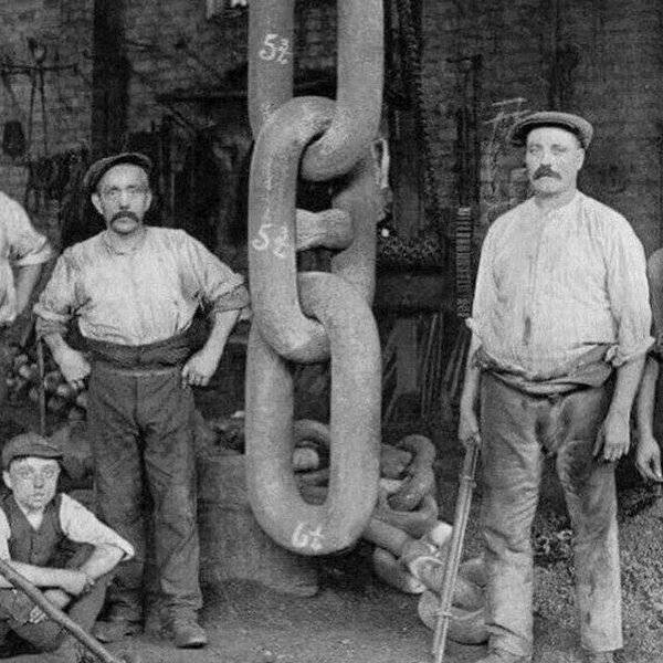 workers standing beside chain for Titanic anchor -1910.jpg