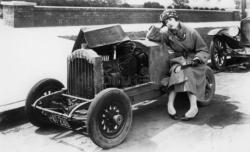 young-woman-sitting-next-to-small-car-looking-engine-disbelieve-52027700.jpg